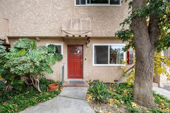 Front view of a two-story house with a red door and awning.