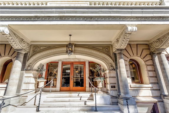 Front view of a building entrance with ornamental architecture and steps.