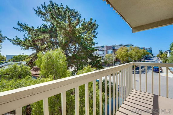 View from a balcony showing trees and nearby buildings.