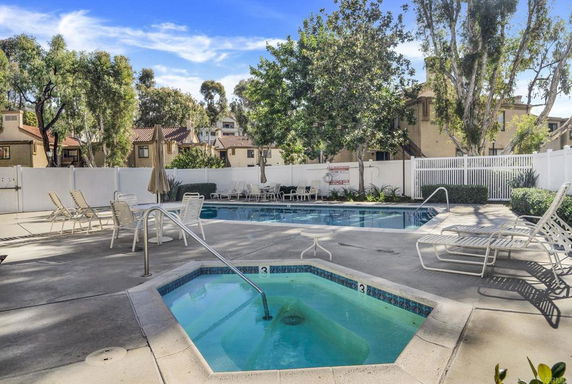 Outdoor view of a swimming pool area with lounge chairs and trees.