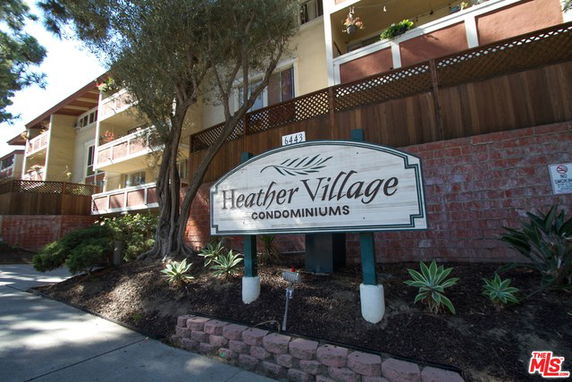Front view of a condominium building with multiple stories and a sign for Heather Village Condominiums.