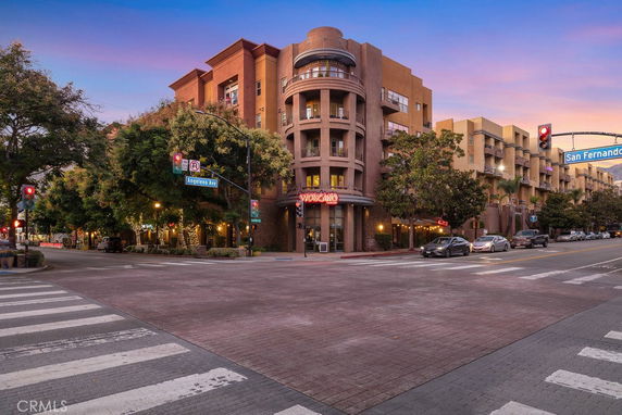 Front view of a multi-story building with rounded balconies at a street corner.