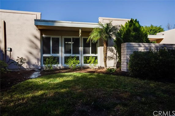 Front view of a single-story house with large windows and a small garden.
