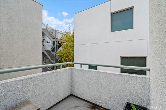 View of modern buildings from a balcony, featuring white walls and rectangular windows.