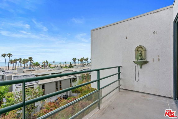 View of surrounding area with palm trees and ocean from a building balcony.