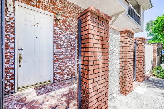 Front view of a red brick house entrance with a white door and columns.