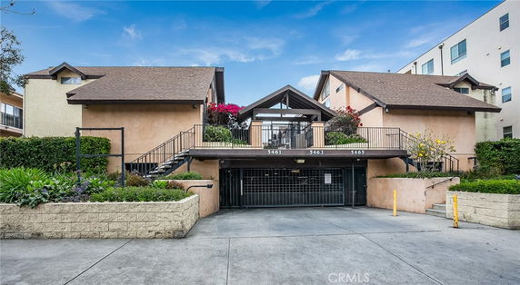 Front view of a multi-unit residential building with a gated entrance and outdoor stairs.
