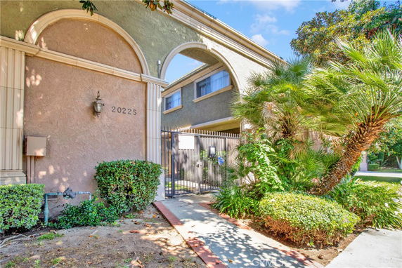 Front view of a residential building with an arched entrance and gated access.