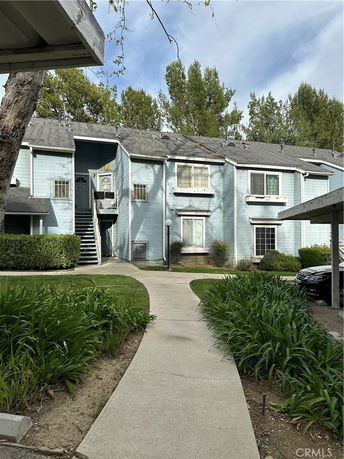 Front view of a two-story blue townhouse with a small porch and stairs.