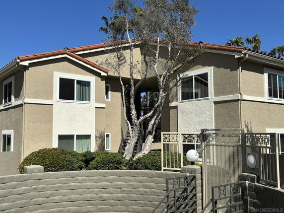 Front view of a two-story building with a staircase and surrounding landscaping.