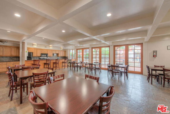 Indoor club house area with dining tables and kitchenette.