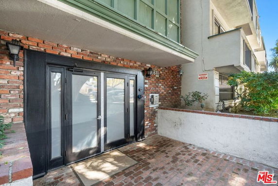 Front view of a building entrance with brick facade and glass double doors.