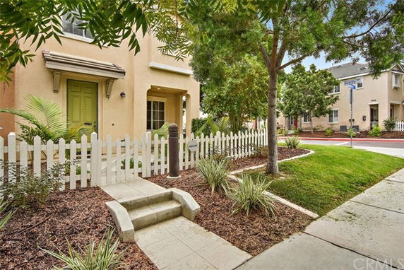Front view of a house with a small porch and a picket fence.