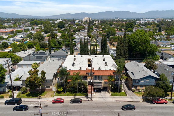 Aerial view of a neighborhood with various houses and a central building along a street.
