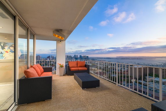 Outdoor balcony with seating area offering a panoramic view of the city and waterfront.