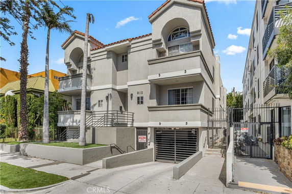 Front view of a multi-story residential building with balconies and gated entrance.