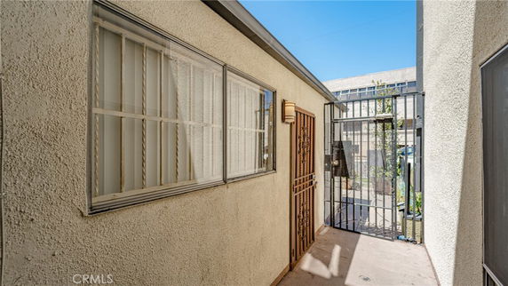 Side view of a building with metal barred windows and a metal gate.