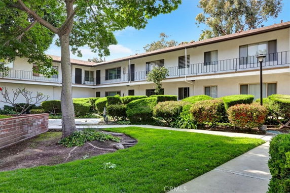 Front view of a two-story building with balconies and hedges.