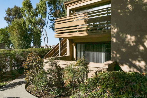Front view of a multi-story building with wooden railings and a window on the lower level.