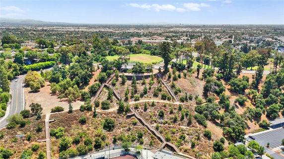 Panoramic view of a landscape with greenery and trees, overlooking a cityscape in the distance.