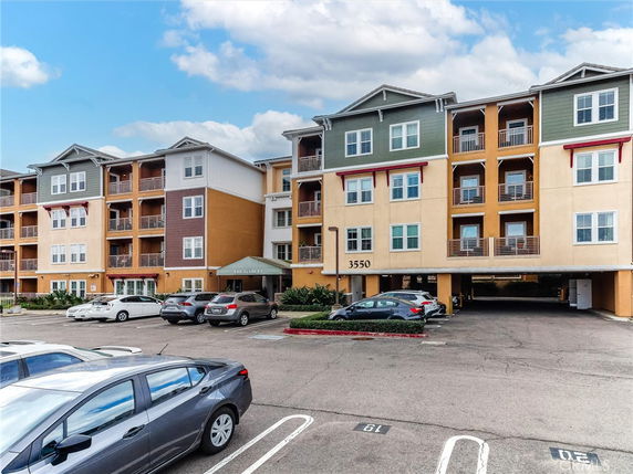 Front view of a multi-story building with balconies and parking area.
