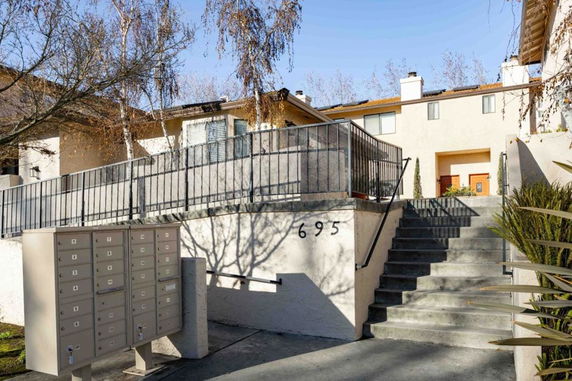 Front view of a multi-story residential building with stairs leading to the entrance.