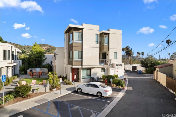 Front view of a modern three-story house with large windows and a small front yard.