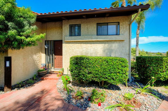 Front view of a two-story house with a red roof and stucco exterior.