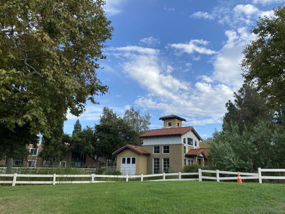 Front view of a two-story house with a tower and red-tiled roof.