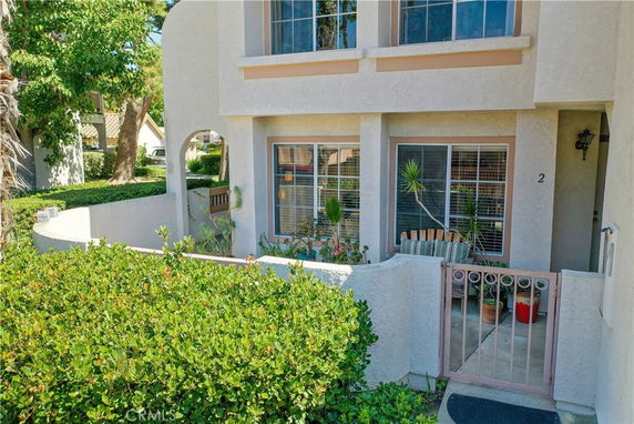 Front view of a two-story house with a small patio and gated entrance.