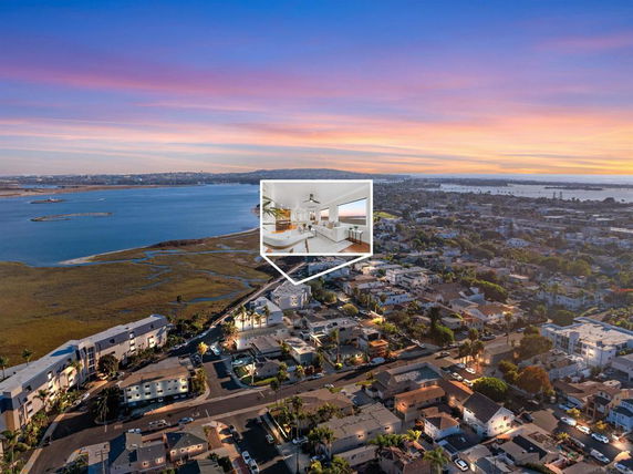 Aerial panoramic view of a coastal town with a large water body at sunset.