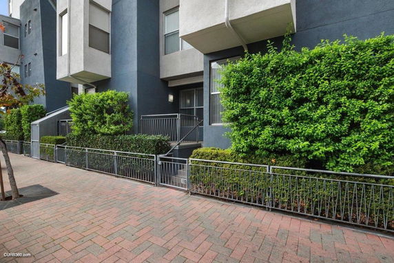 Front view of a modern multi-story building with a small staircase and greenery.
