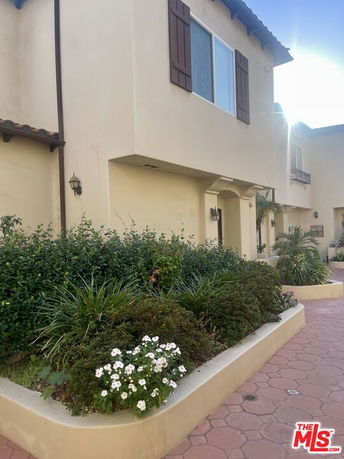 Front view of a two-story house with shutters and a small garden area.