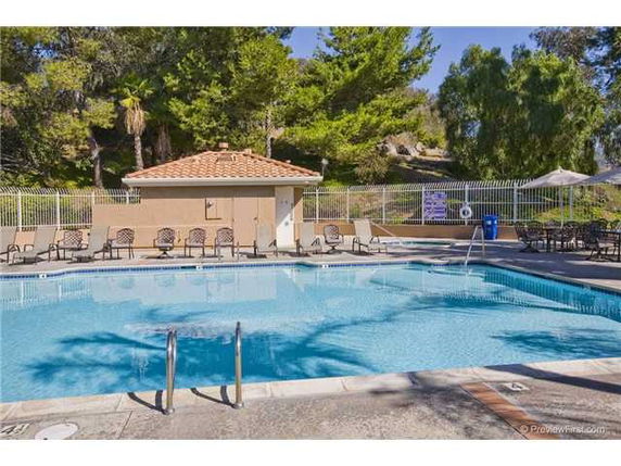 Outdoor swimming pool area with chairs and a fenced enclosure.