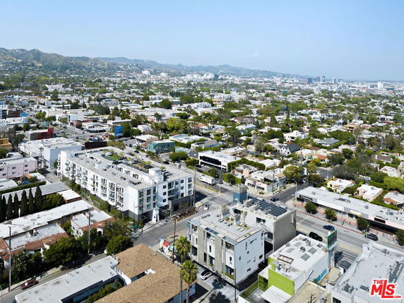 Panoramic view of a cityscape with multiple buildings and roads, surrounded by distant hills.