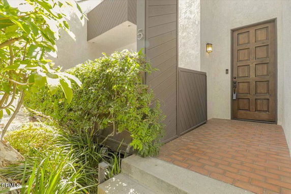 Front entrance of a house with a wooden door and brick pathway.