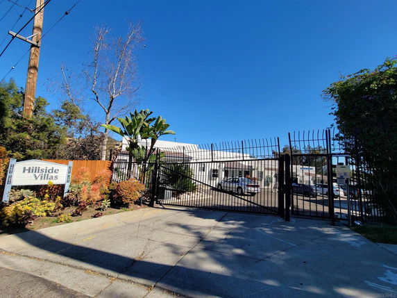 Front view of a gated community with a sign reading 'Hillside Villas'.