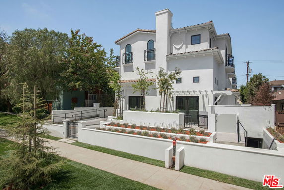 Front view of a multi-story house with balconies and a landscaped entrance.