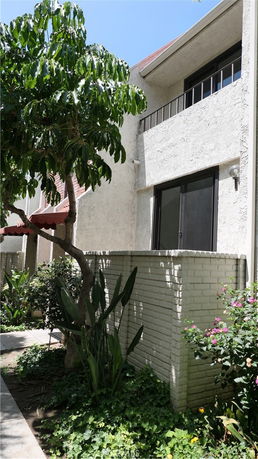 Front view of a two-story house with a stucco facade and a small balcony.