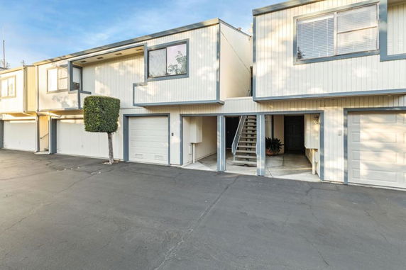 Front view of a row of townhouse units with garages and an external staircase.