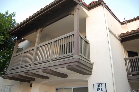 View of a residential building exterior with a balcony and brown railing.