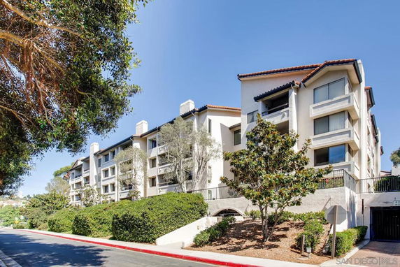 Front view of a multi-story residential building with balconies and a tiled roof.
