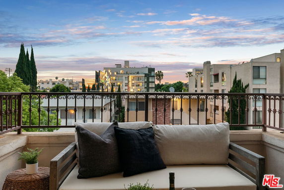 View of surrounding buildings from a balcony with seating and decorative accents.