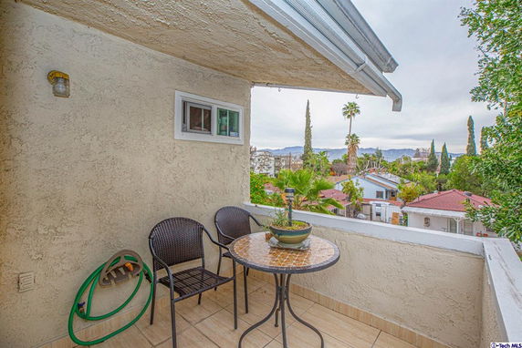Balcony view overlooking residential area with trees and distant mountains