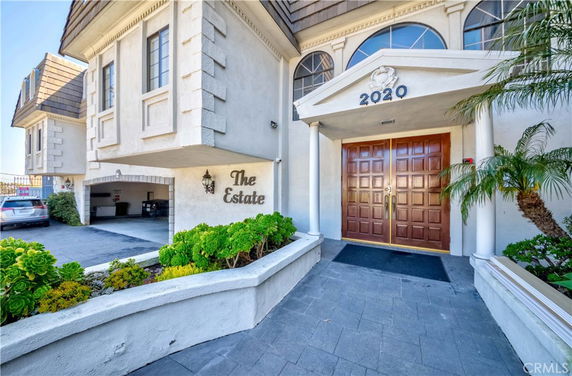 Front view of a building entrance with double wooden doors and columns.