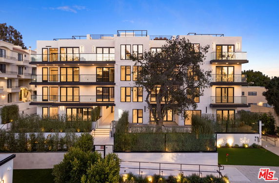 Front view of a multi-story modern apartment building with large windows and balconies.