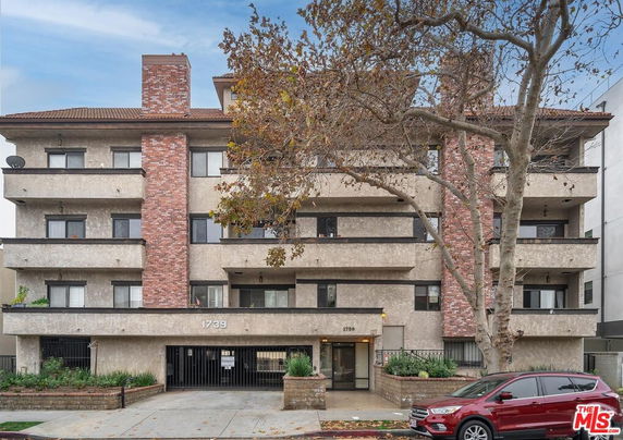 Front view of a multi-story residential building with brick accents and balconies.
