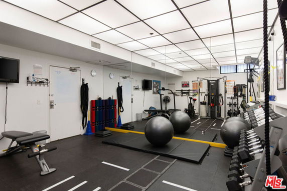 Indoor gym with various exercise equipment, mirrors, and bright ceiling lights.