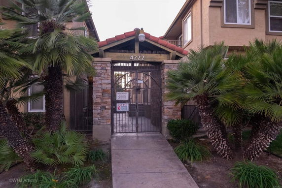 Front view of a gated entrance to a residential building with stone accents and a tile roof.