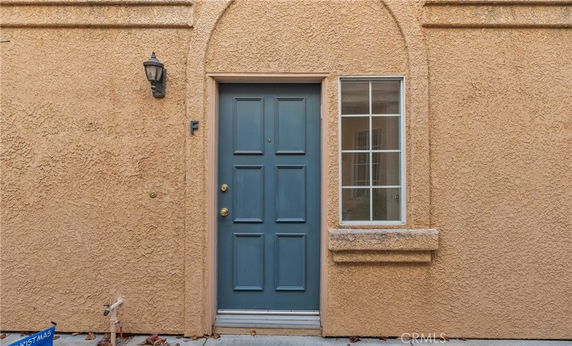 Front view of a building entrance with a blue door and a window.